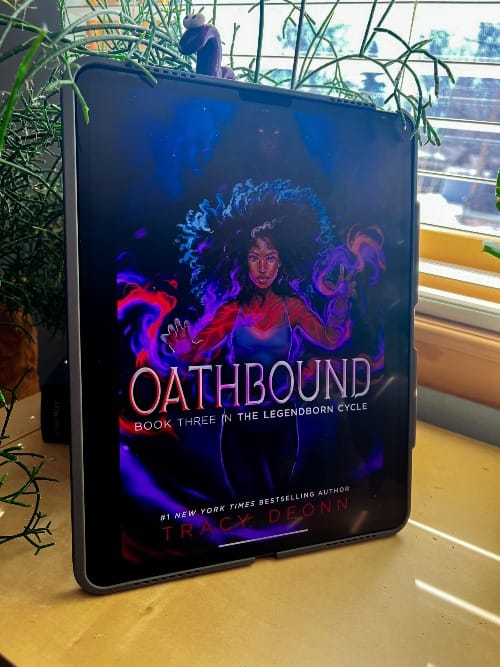 Oathbound by Tracy Deonn is displayed on an iPad leaning against a black planter