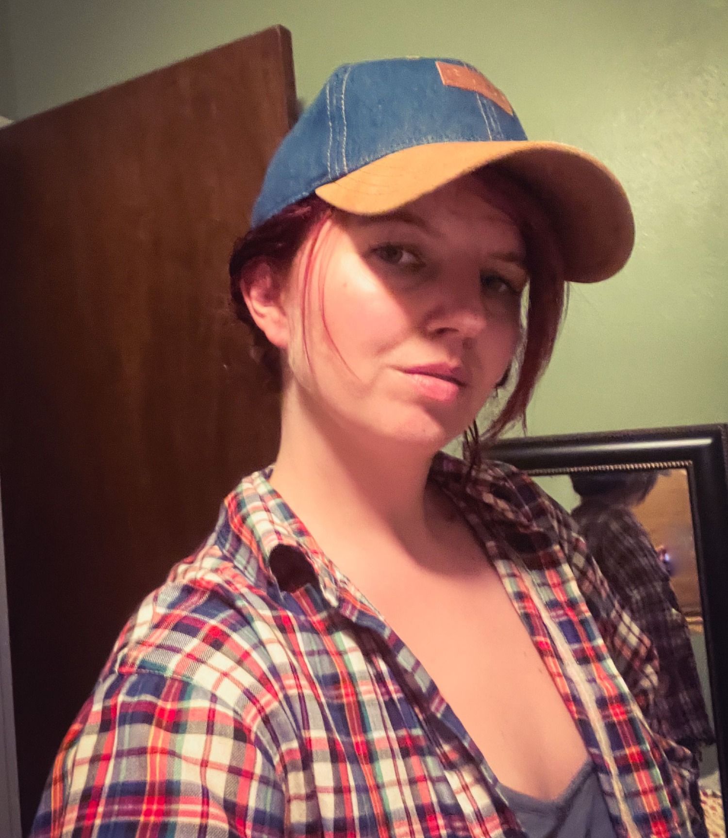 White woman wearing a hat and red plaid shirt