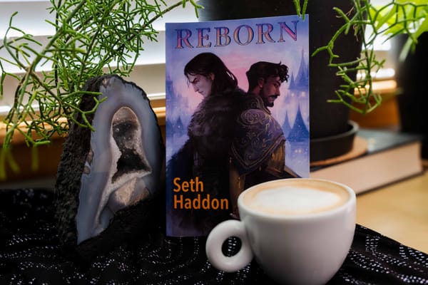 Reborn book sitting up right behind a coffee and next to a geoid. 