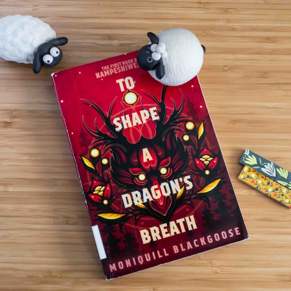 To Shape a Dragon's Breath book laying on a bamboo with two sheep figurines
